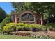 Welcoming Towne Lake Hills brick community entrance adorned with flags and vibrant landscaping at 320 Ironhill Trce, Woodstock, GA 30189