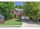 Attractive brick home with lush green lawn, mature trees, and an extended driveway leading to a two-car garage at 320 Ironhill Trce, Woodstock, GA 30189