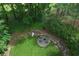 A charming stone fire pit area with seating, surrounded by a lush lawn and mature landscaping at 320 Ironhill Trce, Woodstock, GA 30189