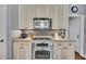 Close-up view of the kitchen featuring stainless steel oven, microwave, cooktop, and shaker cabinets at 320 Ironhill Trce, Woodstock, GA 30189