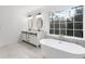 Bright bathroom featuring a soaking tub, double vanity, marble floors, and a large window at 816 Ivy Ridge Dr, Loganville, GA 30052