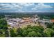 Expansive aerial view of a mixed-use community surrounded by lush green trees, neighborhood offering a blend of residential and commercial spaces at 965 Under Ct, Sugar Hill, GA 30518