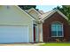 Close-up of home's exterior with brick accents, two-car garage and a red door at 965 Under Ct, Sugar Hill, GA 30518