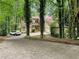 Inviting home exterior with stone and siding, a two-car garage, and a long driveway in wooded setting at 10320 Crescent Ridge Dr, Roswell, GA 30076