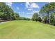 View of the lush green golf course surrounded by trees and blue skies, creating a picturesque landscape at 2313 Saint Davids Nw Sq # 12, Kennesaw, GA 30152