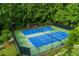 Aerial view of fenced tennis courts nestled among lush greenery, providing a private recreational space at 2882 Clary Hill Ne Dr, Roswell, GA 30075