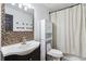 Well lit bathroom with a decorative mirror, modern vanity, tiled accent wall and shower with curtain at 870 Underhill Ct, Sugar Hill, GA 30518