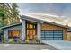 Contemporary home boasting a unique roofline, stone accents, and a modern glass garage door at 21 Elm St, Hampton, GA 30228