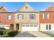 Charming townhome features a brick and tan facade, attached garage, and manicured landscaping at 7177 Fringe Flower Dr, Austell, GA 30168