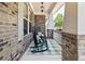 Inviting front porch with brick facade, rocking chairs, and stylish green-and-white checkered rug at 337 Spotted Ridge Cir, Woodstock, GA 30188