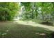 Expansive backyard featuring lush green grass, mature trees, and space for outdoor activities at 2184 E Cherokee Dr, Woodstock, GA 30188