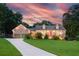 A beautiful home exterior at sunset, featuring a brick facade, manicured lawn, and inviting curb appeal at 2702 Moorings Pkwy, Snellville, GA 30039