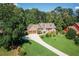 Charming brick home with a lush green lawn, mature trees, and a long driveway leading to a two-car garage at 2702 Moorings Pkwy, Snellville, GA 30039