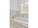 Bright bathroom featuring a jacuzzi tub with marble tiling and a view to the outside at 2702 Moorings Pkwy, Snellville, GA 30039