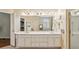 Bathroom with double sink vanity, large mirror, white cabinets, and a view of the tub at 4070 Ridgehurst Se Dr, Smyrna, GA 30080