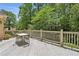 Outdoor deck with railing is ideal for relaxing, featuring wood floors and wrought-iron table with chairs, surrounded by lush trees at 4070 Ridgehurst Se Dr, Smyrna, GA 30080