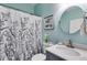 Bathroom with blue walls, patterned shower curtain, framed mirror, and ample lighting at 5200 Woodmont Dr, Villa Rica, GA 30180