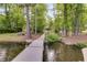 Scenic view of a wooden dock extending into the water, surrounded by mature trees and landscaping at 5200 Woodmont Dr, Villa Rica, GA 30180