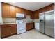 Well-lit kitchen boasts wooden cabinetry, a stainless refrigerator and white appliances at 115 Delmoor Nw Dr, Atlanta, GA 30311