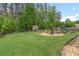 Beautifully landscaped backyard with a fire pit, play area, and mature trees for privacy at 31 Copper Leaf Ct, Villa Rica, GA 30180