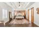 Spacious main bedroom with wood floors, brick accent wall, decorative rug, and tray ceiling with ceiling fan at 31 Copper Leaf Ct, Villa Rica, GA 30180