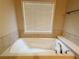 Close up of a soaking tub with tile surround and decorative fixtures in the primary bathroom at 139 Vinca Cir, Suwanee, GA 30024