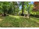Secluded backyard featuring mature trees, lush lawn, wooden chairs and a fire pit for serene outdoor enjoyment at 530 Twinflower Ct, Roswell, GA 30075