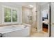 Bright bathroom features a soaking tub, shower with glass enclosure, and plantation shutters for natural light and privacy at 530 Twinflower Ct, Roswell, GA 30075