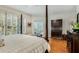 Cozy main bedroom featuring a four-poster bed, dresser, and large windows with shuttered blinds at 530 Twinflower Ct, Roswell, GA 30075