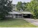 Charming single-story home with a covered parking area and a well-maintained front yard surrounded by mature trees at 1176 Cardinal Ne Rd, Conyers, GA 30012