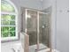 Modern bathroom featuring a glass-enclosed shower with gray tile, alongside a soaking tub and large window at 2595 Glaramara Ter, Cumming, GA 30041