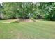 Large grassy backyard with mature trees providing shade and a wooded backdrop at 662 Shady Willow Ln, Loganville, GA 30052