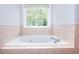 Corner garden tub with tile surround near window at 662 Shady Willow Ln, Loganville, GA 30052