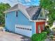 Side view of a blue home with a white garage door, brick accents, and lush greenery at 662 Shady Willow Ln, Loganville, GA 30052
