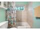 Tiled bathroom with tub and shower features a leaf patterned shower curtain and window at 118 Lucia Dr, Smyrna, GA 30082