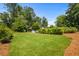 Expansive backyard featuring lush green grass and mature trees, with home nestled in the background at 1691 Whitlock Rd, Marietta, GA 30066
