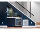 Stylish wet bar with modern finishes, wine refrigerator, and striking dark blue cabinetry beneath the staircase at 2001 Swazey Dr, Decatur, GA 30032