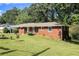 This is an exterior view of the brick home, with lawn, and mature trees on a sunny day at 3055 Henderson Mill Rd, Atlanta, GA 30341