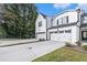 A view of a modern white townhouse with attached garage, complemented by a concrete driveway and manicured landscaping at 1704 Hyssop Se Blvd, Smyrna, GA 30126