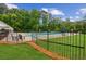 Community pool with lounge chairs surrounded by a black fence and lush greenery at 111 Trellis Ct, Acworth, GA 30101