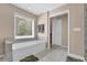 Bathroom featuring a white soaking tub with tile accents and a large window at 590 Kyle Trace Ct, Sugar Hill, GA 30518