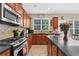 Kitchen featuring a stainless-steel stove, granite counters, wood cabinets and hardwood floors at 590 Kyle Trace Ct, Sugar Hill, GA 30518