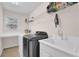 Well-organized laundry room featuring a modern washer and dryer, sink, and ample shelving space at 590 Kyle Trace Ct, Sugar Hill, GA 30518