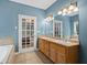 Bathroom with dual sinks, tile floors, framed mirror, soaking tub, and shower with glass door at 239 Berry Rd, Mcdonough, GA 30252