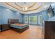 Bright main bedroom with bay windows, tray ceiling, and warm wood flooring at 239 Berry Rd, Mcdonough, GA 30252