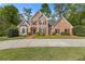 Charming brick home with manicured lawn and mature landscaping, black shutters, and a concrete driveway at 1750 Providence Place Dr, Alpharetta, GA 30009