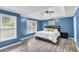 Spacious blue bedroom features a tray ceiling, large windows, and wood-look flooring at 947 Summer Forest Drive, Suwanee, GA 30024