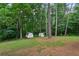 Large backyard with grassy lawn and storage sheds surrounded by mature trees at 232 Apple Branch Dr, Woodstock, GA 30188