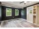 Bedroom with dark walls, two windows, ceiling fan, grey wood-look flooring, and an open closet at 232 Apple Branch Dr, Woodstock, GA 30188