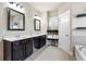 A bathroom features a double sink vanity, shelves with towels, and a soaking tub next to a window at 411 Ridgeway Ln, Canton, GA 30114